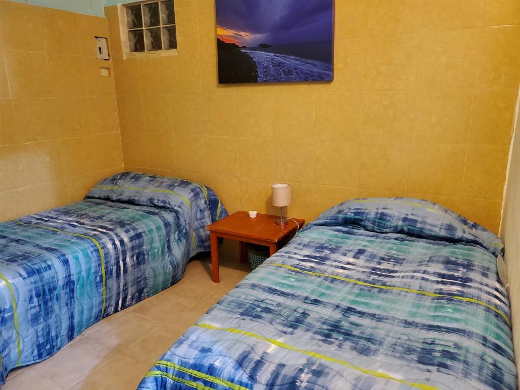 a room with two beds and a table in it at Malecon Beach House in Progreso 1 block from beach in Progreso