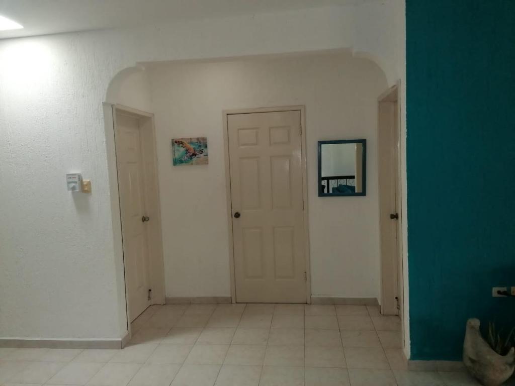 an empty hallway with a white door and a green wall at Malecon Beach House in Progreso 1 block from beach in Progreso