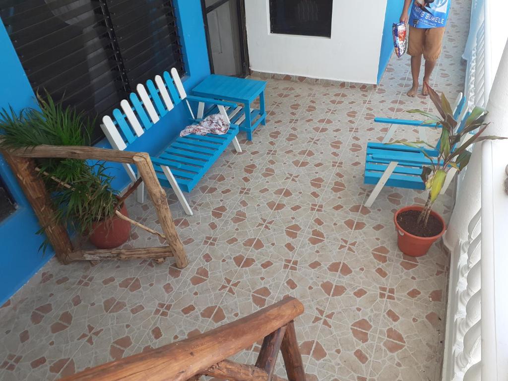 a balcony with two blue chairs and potted plants at Malecon Beach House in Progreso 1 block from beach in Progreso