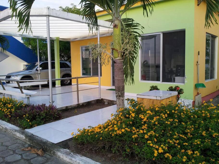 a house with a palm tree and a car in the driveway at VILLA SANTORO Casa playa de Castelnuovo-Atacames in Atacames