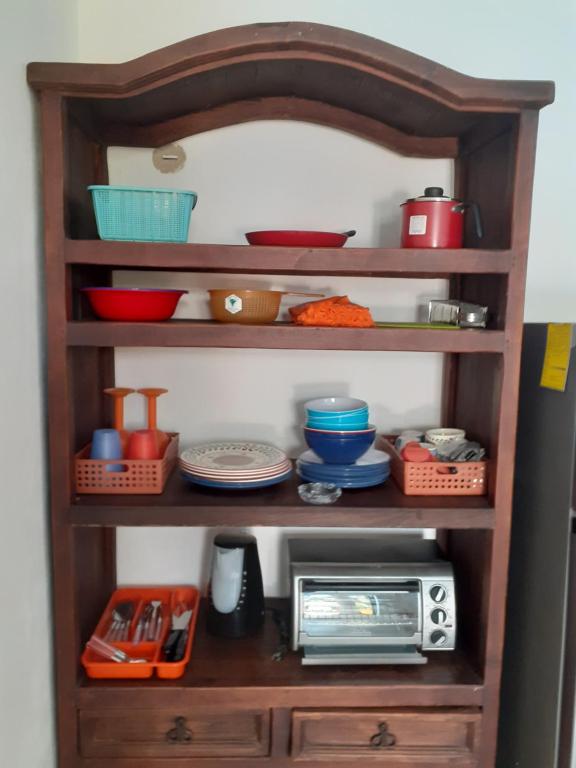 a shelf with bowls and plates and a microwave at Malecon Beach House in Progreso 1 block from beach in Progreso