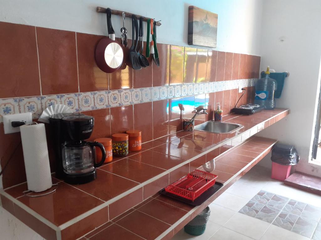 a kitchen with a counter with a sink and a clock at Malecon Beach House in Progreso 1 block from beach in Progreso