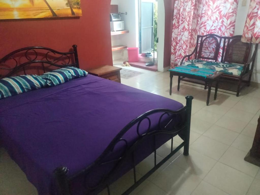 a bedroom with a purple bed and a chair at Malecon Beach House in Progreso 1 block from beach in Progreso