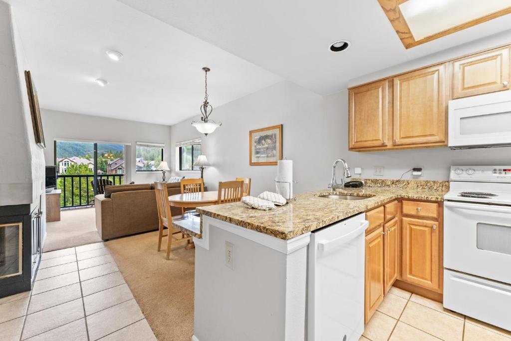 Una cocina con electrodomésticos blancos y una sala de estar. en Greens at Copper 219 by Summit County Mountain Retreats, en Copper Mountain