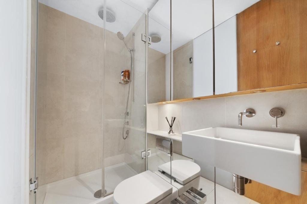 a white bathroom with a sink and a shower at Crawford Street Apartment By Morethanstays in London