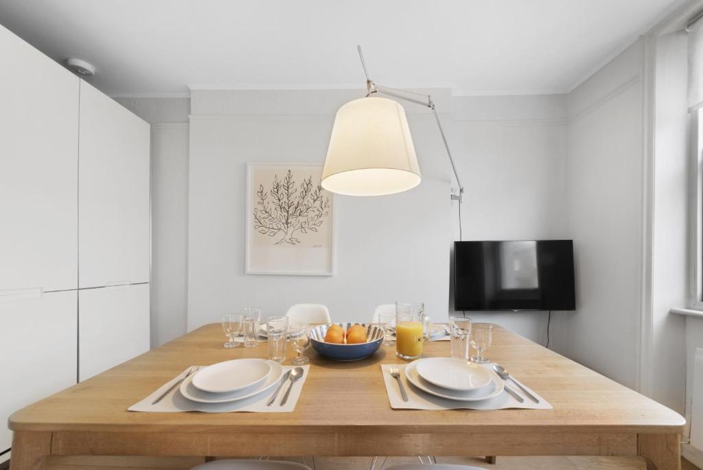 a dining room with a wooden table with plates and glasses at Crawford Street Apartment By Morethanstays in London