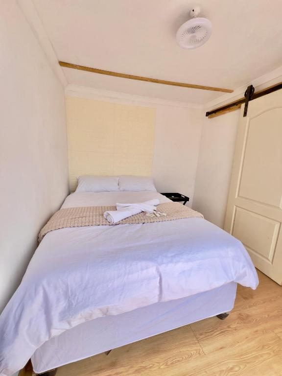 Un dormitorio con una gran cama blanca en una habitación. en Container house, en Burgersfort