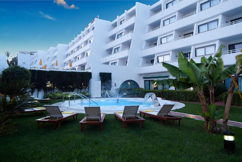 a large white building with chairs and a swimming pool at El Greco in Puerto Rico de Gran Canaria