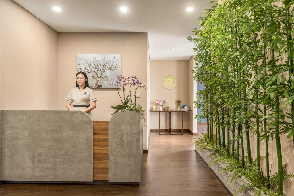 A reception desk with a staff member in a bright, plant-filled lobby.