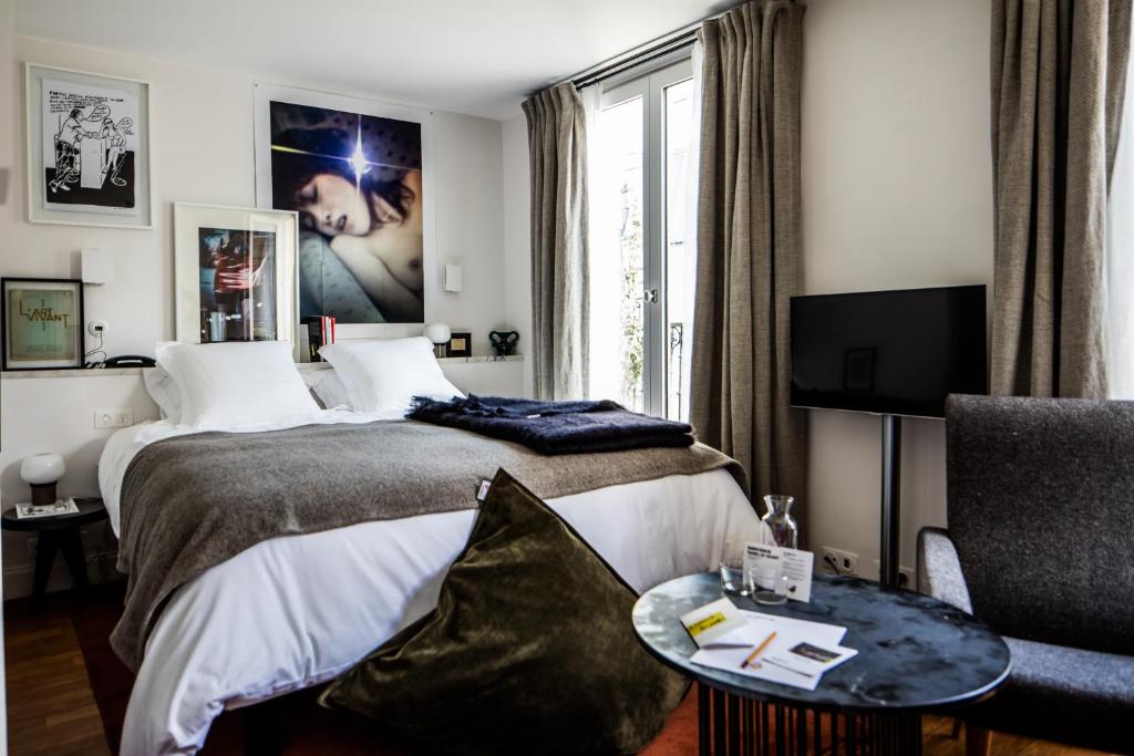 a hotel room with a bed, desk and television at Le Pigalle Hotel in Paris