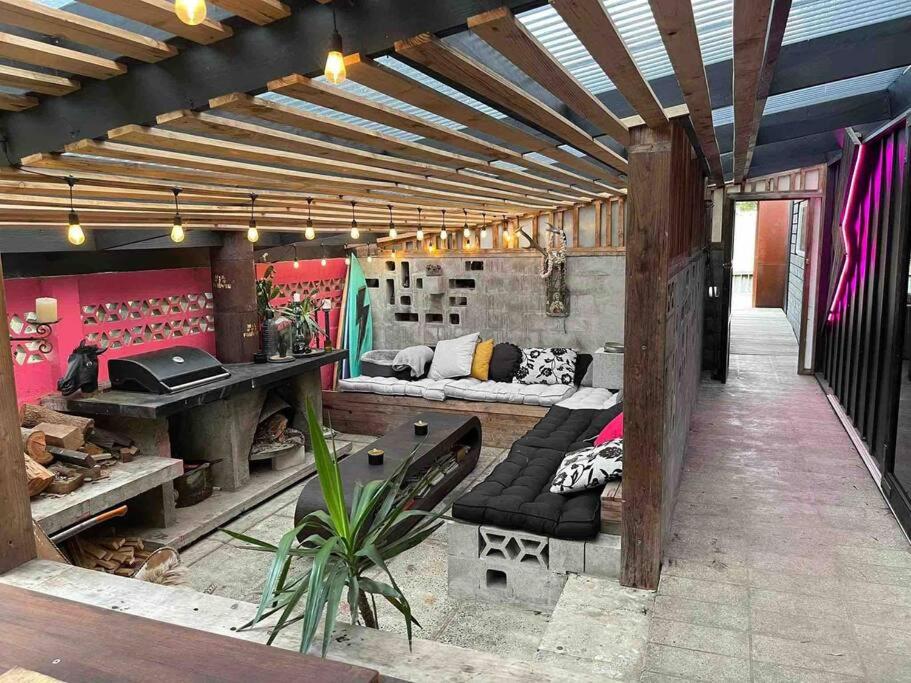 a living room with a table and a couch in a building at Electric Waihi Beach House - family & dog friendly, close to beach, pool table, outdoor fire room, skate ramp in Bowentown
