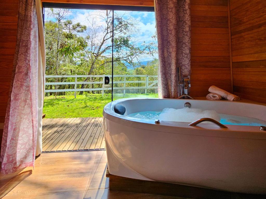 a bath tub in a room with a window at Cabana com Hidromassagem in Bom Retiro