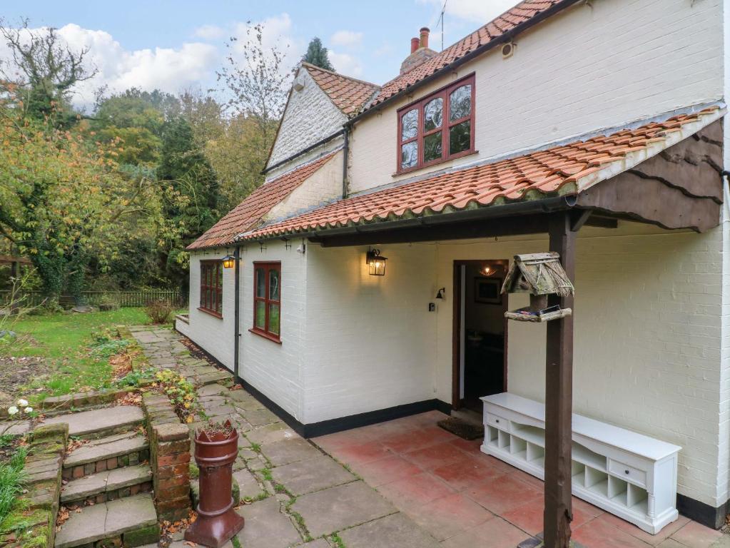 a white house with a porch and a door at Woodpit Cottage in Nottingham