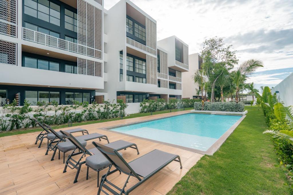 an exterior view of a building with a swimming pool and chairs at Lumina at Flats Punta Cana Village in Punta Cana