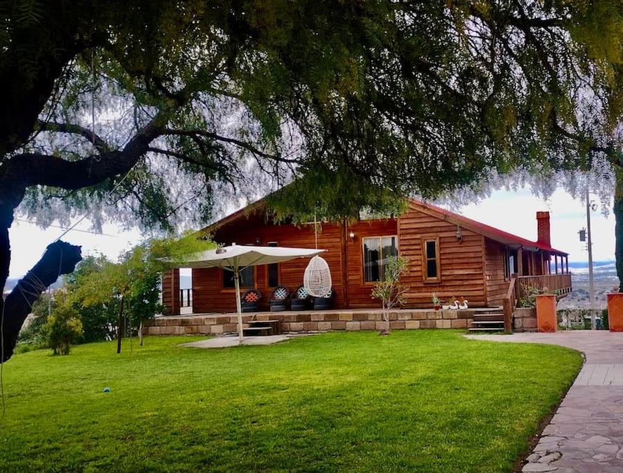 a log cabin with a lawn in front of it at Casa del árbol in Pachuca de Soto