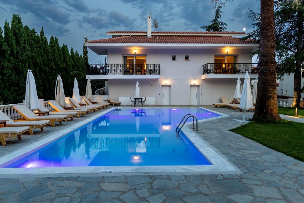 a swimming pool with lounge chairs and a house at Blue Bay Hotel in Iraklitsa