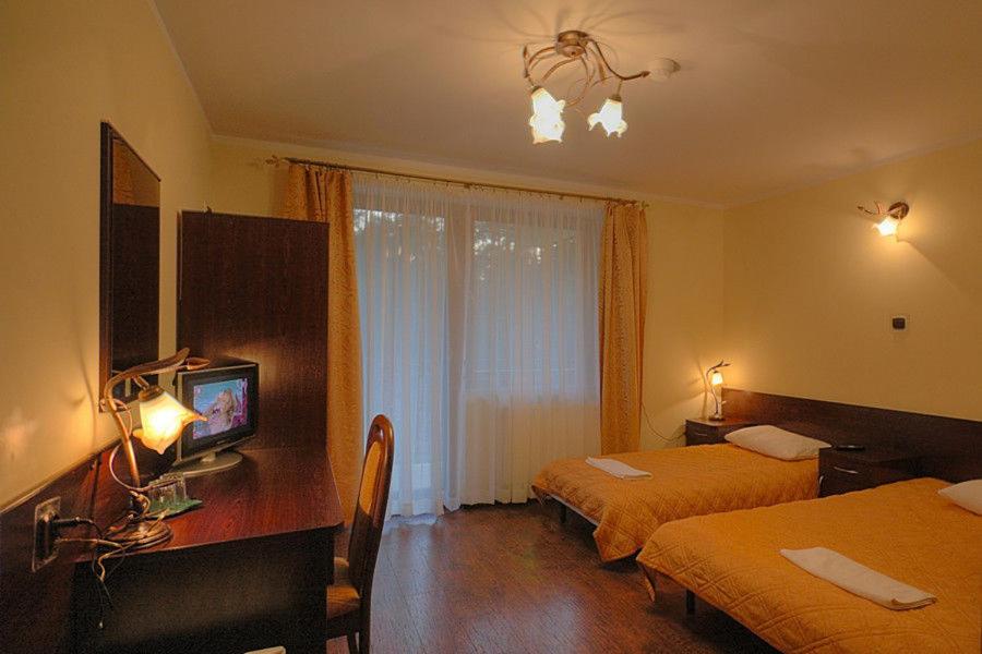 Bedroom with twin beds, desk, and warm lighting.