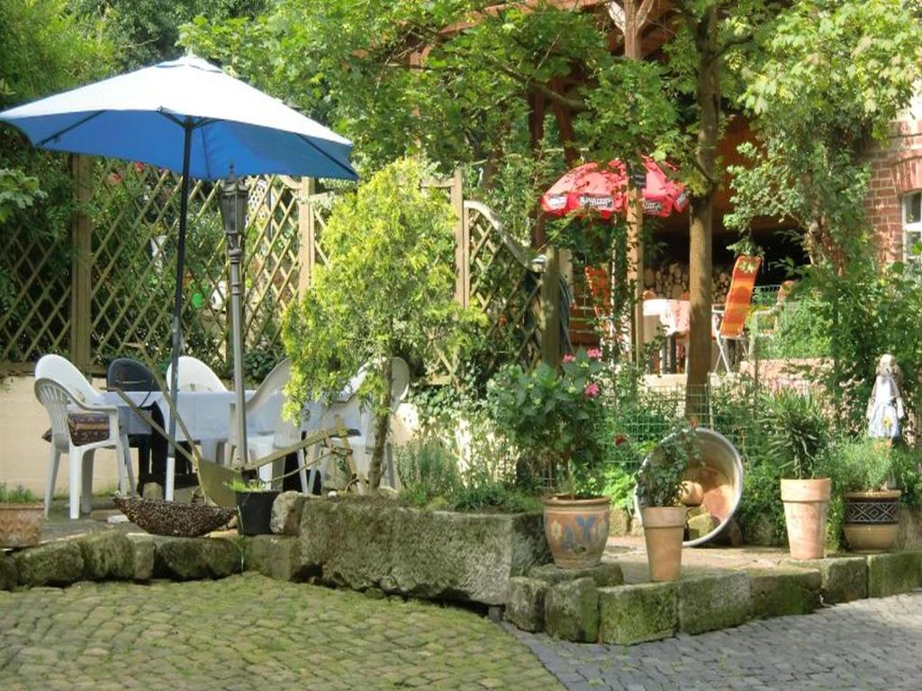 einen Garten mit einem Tisch, Stühlen und einem Sonnenschirm in der Unterkunft Reiterhof Aumühle in Oberaula