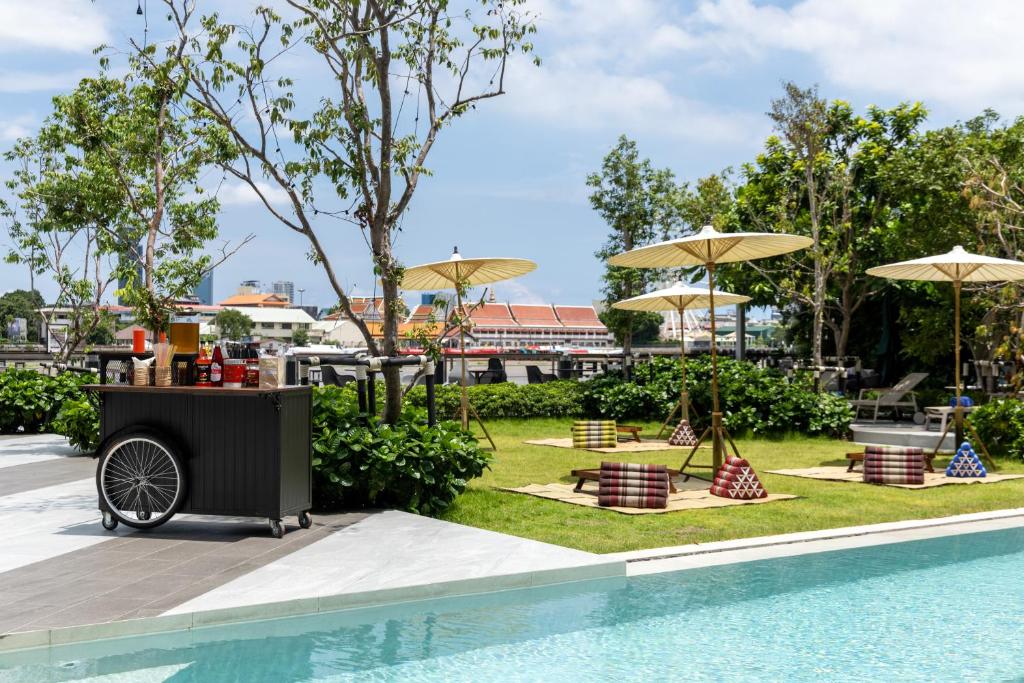 A bright poolside lawn with umbrellas, low seating and a drinks cart.