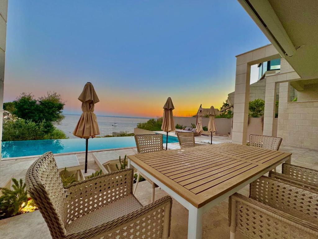 uma mesa e cadeiras de madeira com vista para o oceano em Exclusive villa Kaza - Przno em Budva