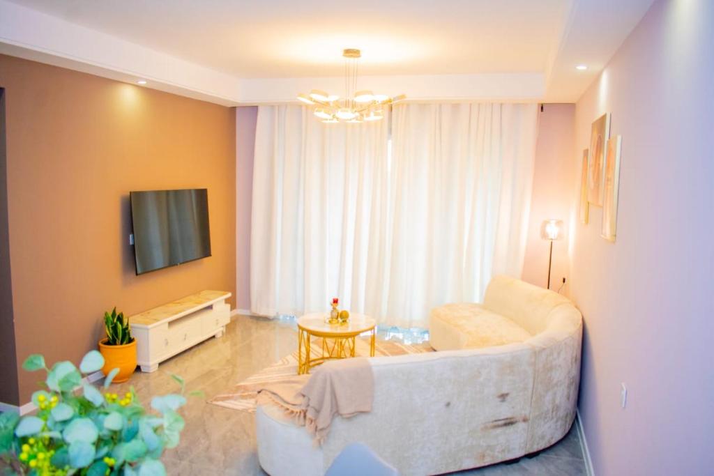 a living room with a white couch and a tv at Modern luxury one bedroom furnished apartment in kilimani in Nairobi