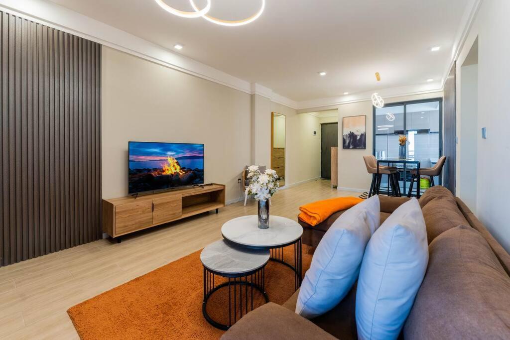 ナイロビにあるKapri Nairobi 2BR Suite w Pool Gym near JKIA SGRのソファとテレビのあるリビングルーム