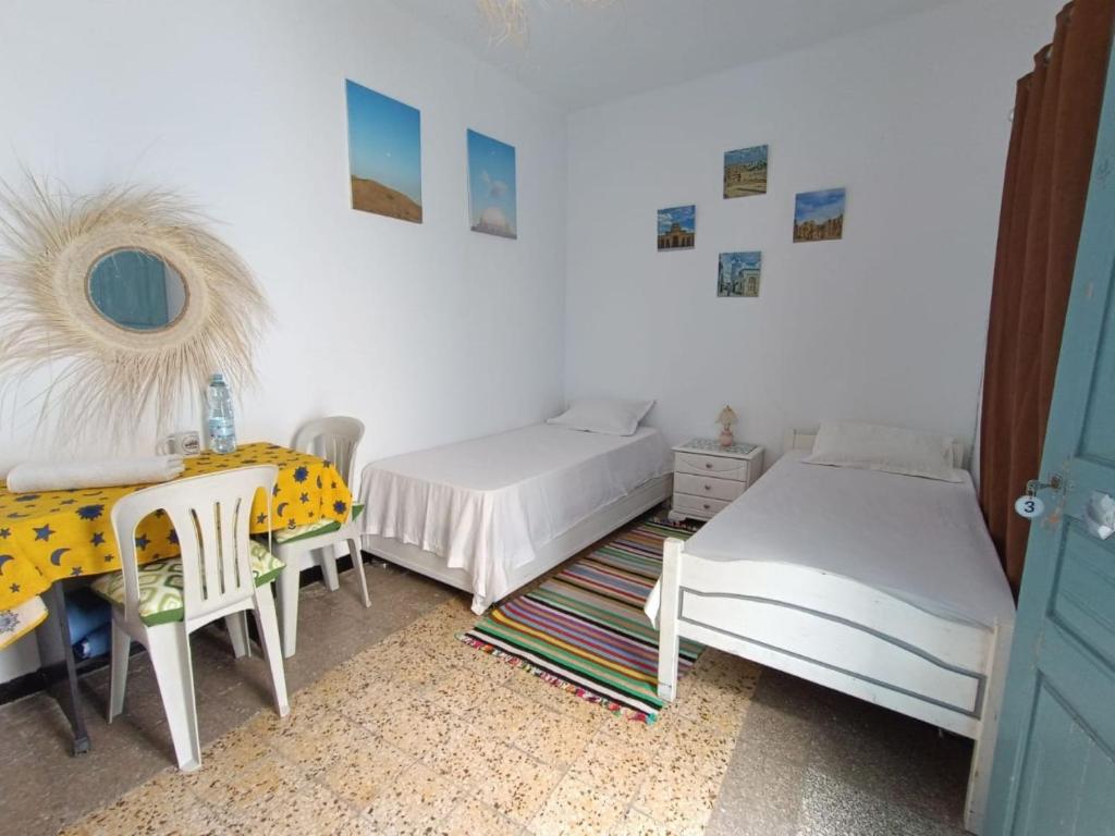 a bedroom with two beds and a table and a mirror at Dar Hkaïem in Sousse