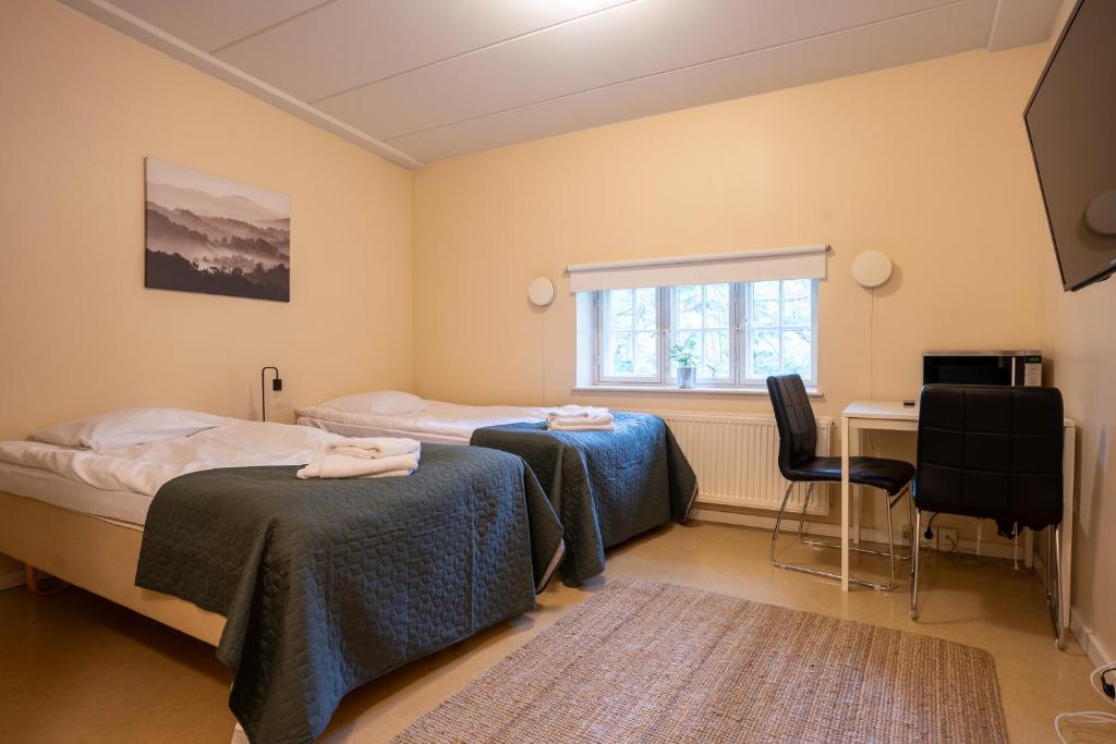 une chambre avec deux lits, un bureau et une fenêtre dans l'établissement Kotimaailma Villa Hortus - Homely Studio for 2, à Turku