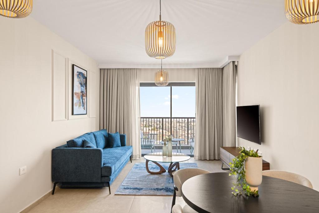 a living room with a blue couch and a table at Yashar Savyon View JLM - 1bd 16th floor in Jerusalem