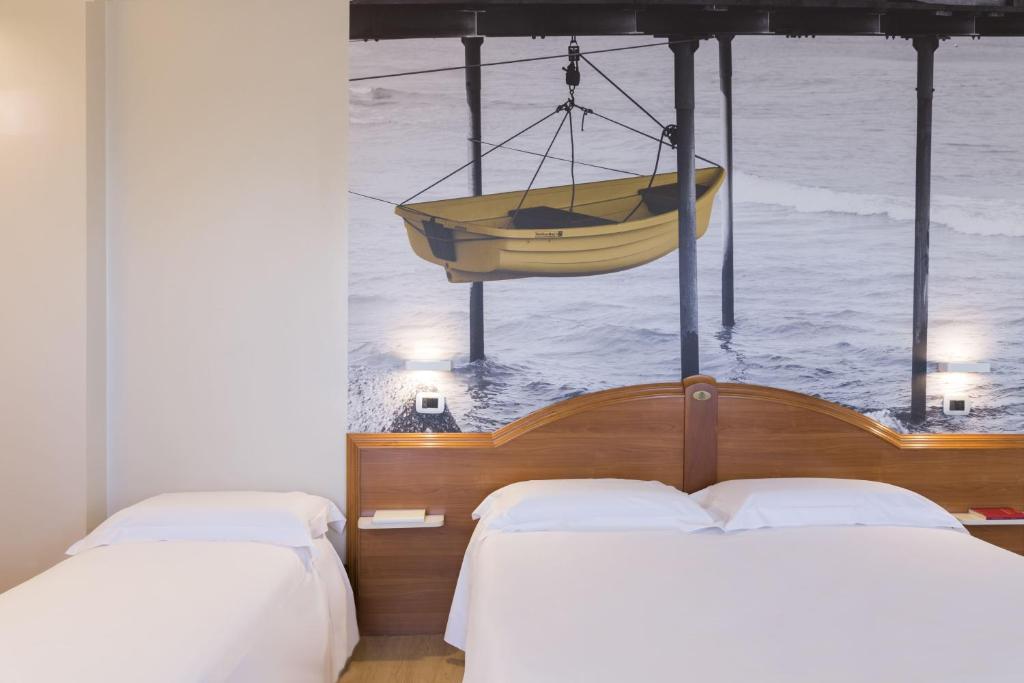 two beds in a room with a boat on the water at B&B Hotel Pescara in Pescara