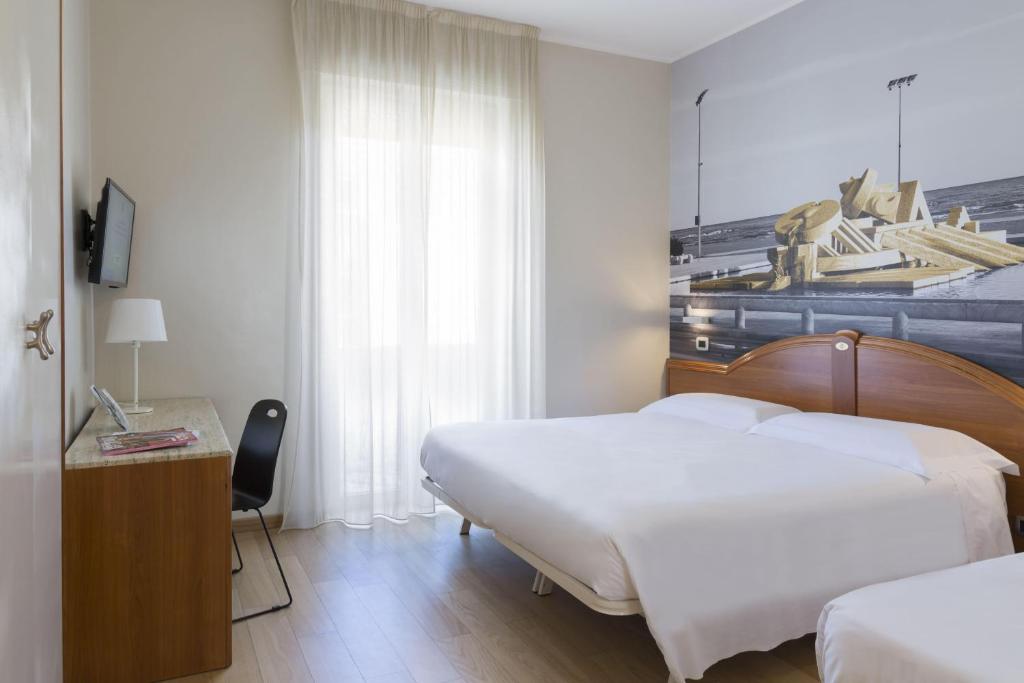 a hotel room with two beds and a desk with a chair at B&B Hotel Pescara in Pescara