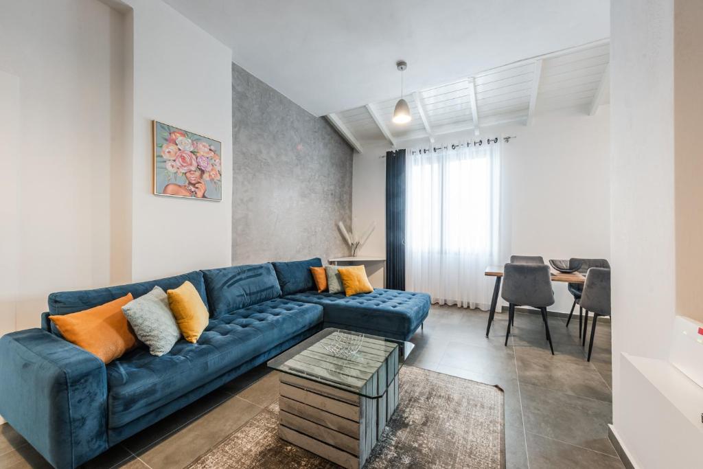 Royal Hill Apartments by PS في دوريس: غرفة معيشة مع أريكة زرقاء وطاولة