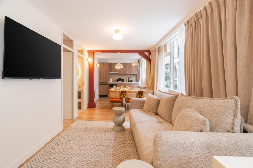 un salon avec un canapé et une télévision à écran plat dans l'établissement Merveilleux appartement de luxe au coeurs de Saint-Germain, à Paris