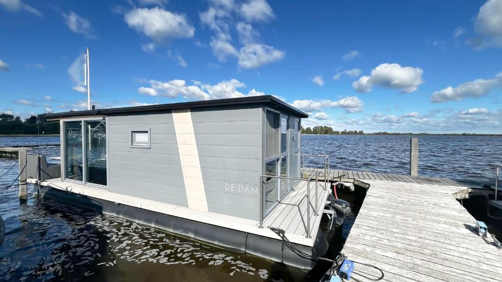 a tiny house on a dock on a body of water at Golfzicht by Droomvilla in Uitgeest