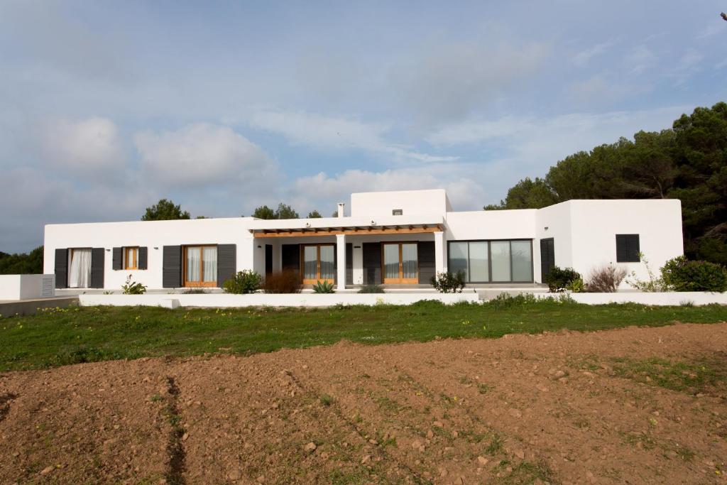 a white house with a field in front of it at Ses Viñas De Cas Baixero in La Mola