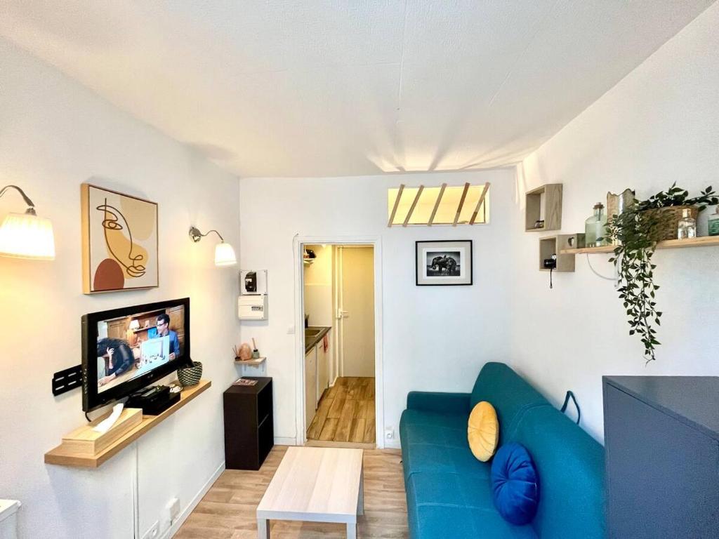 un salon avec un canapé bleu et une télévision dans l'établissement Appartement Studio cosy 17ème, à Paris