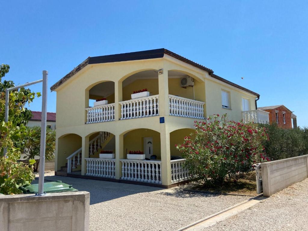 une grande maison jaune avec un balcon dans l'établissement Apartment Draga, à Vir