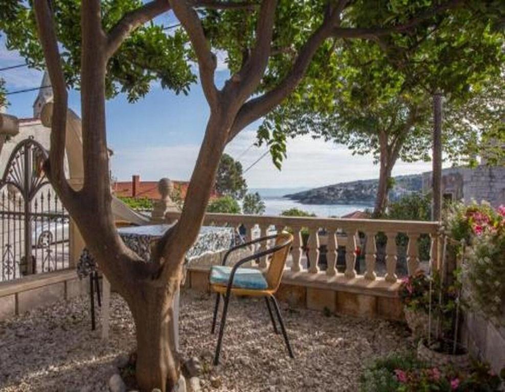 a chair sitting under a tree next to a fence at Apartments and Room Anita in Sumartin