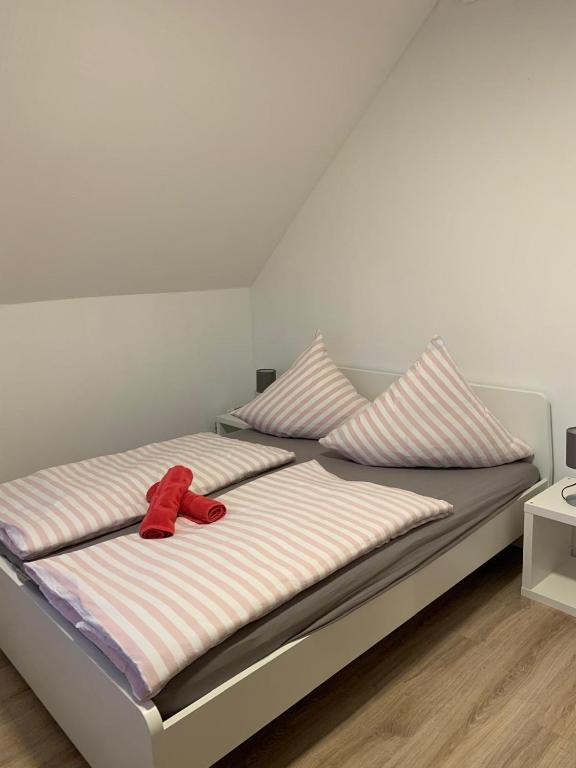 ein rotes Band, das auf einem Bett mit zwei Kissen liegt. in der Unterkunft Fewo Meschede Eversberg Radring in Meschede