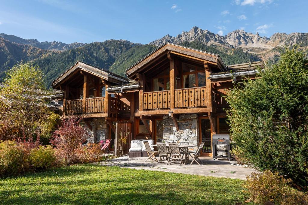 une cabane en rondins avec une terrasse, une table et des chaises dans l'établissement Chalet Kaiya - Alpes Travel - Les Praz - sleeps 8, à Chamonix-Mont-Blanc