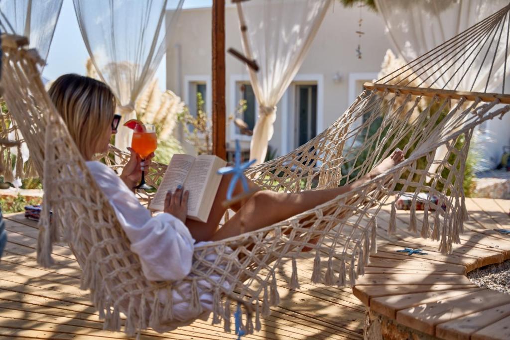 a woman sitting in a hammock reading a book at Althea Boutique Hotel - Adults Only in Amoopi