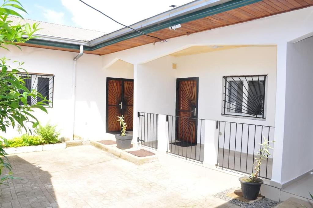 a white house with a porch and a fence at Residence Merveilles CM15 in Kribi