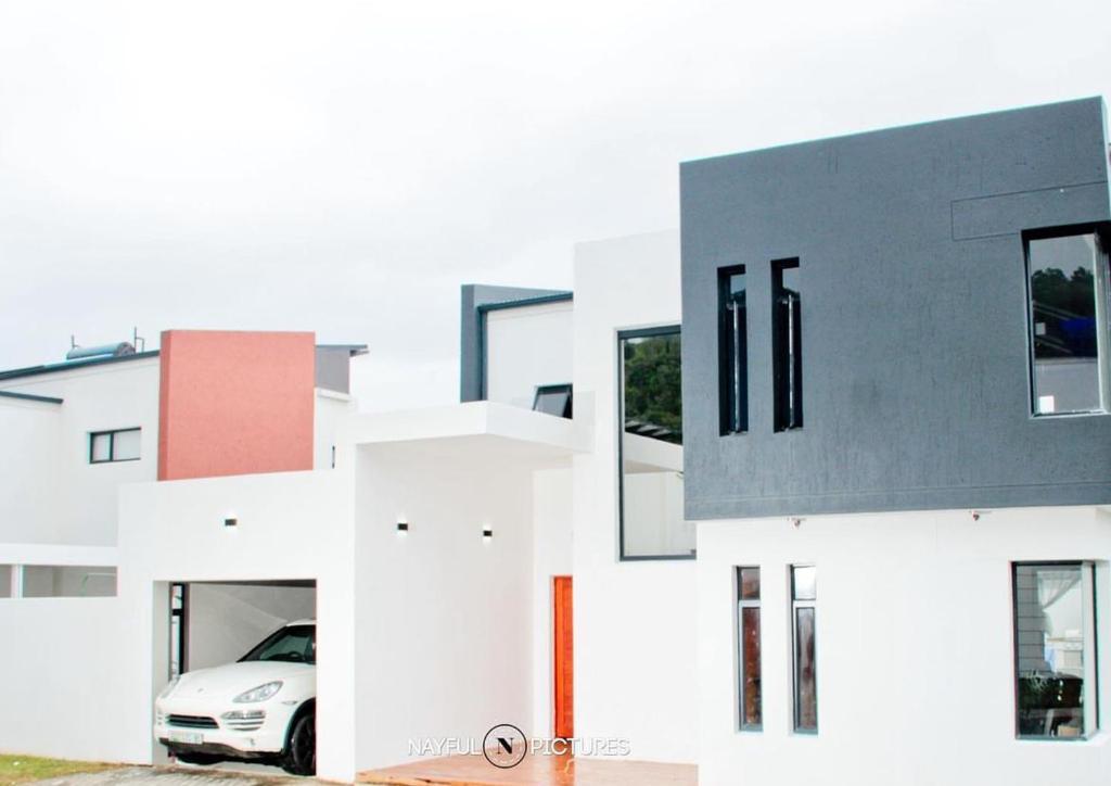Un edificio blanco con un coche aparcado delante. en Roloma Property, en East London