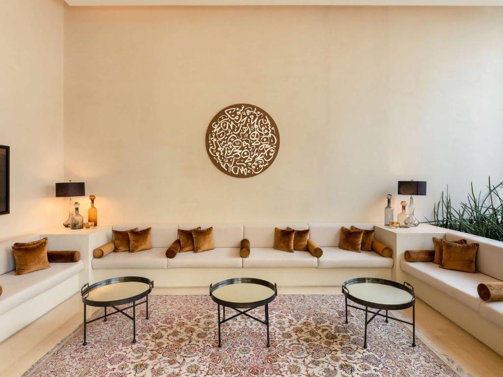 a living room with a couch and two tables at Alwadi Hotel Doha - MGallery Collection in Doha