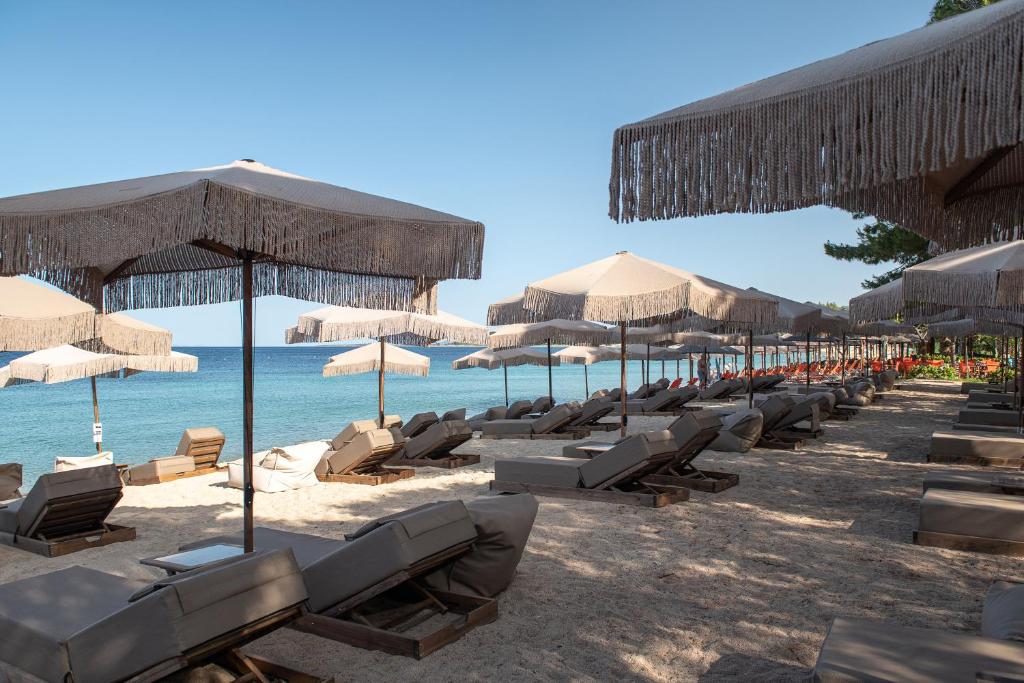 a row of chairs and umbrellas on a beach at Oniro Boutique Hotel in Toroni