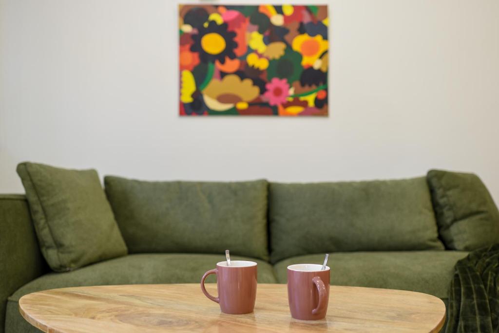 dos tazas de café en una mesa de madera frente a un sofá en T2 Calme absolu - Coeur Toulouse - Saint Cyprien - climatisation - Terrasse arborée, en Toulouse