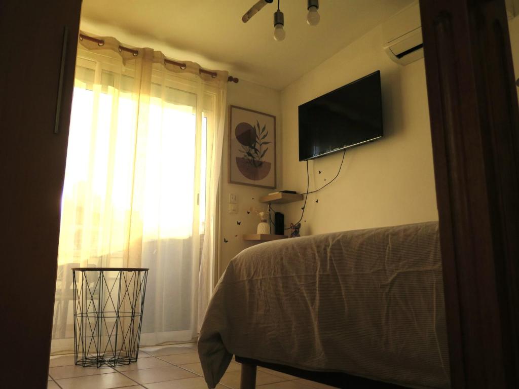 a bedroom with a bed and a window with a television at Maison de village à 35 m du bord de mer in Marseille