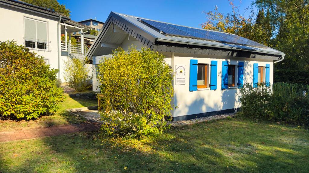 een klein wit huis met blauwe ramen en een tuin bij Ferienhaus Seepferdchen in Göhren