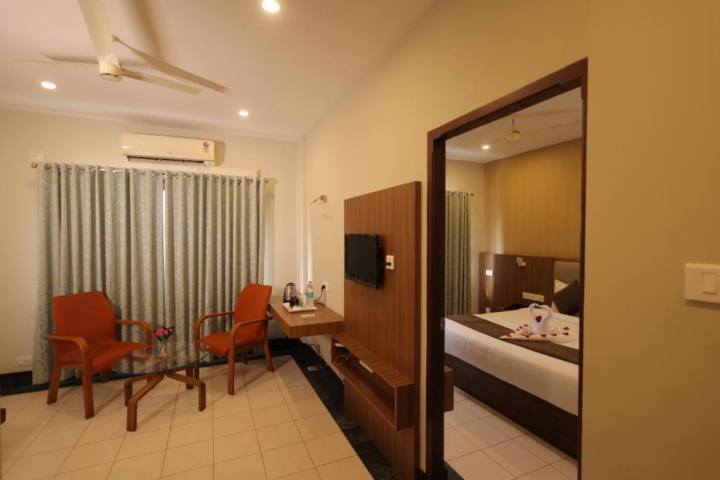a hotel room with a bed and a table and chairs at Nexstay Hotel Calicut Gate in Kozhikode