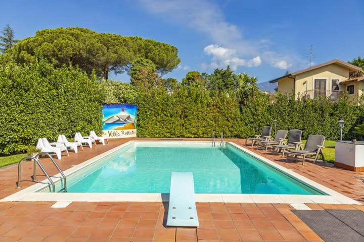 a swimming pool with chairs and a sign in a yard at Casa Vacanza Villa Romano in Nicolosi